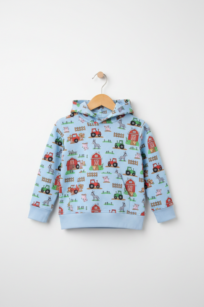 A light blue children's hooded sweatshirt with a colorful farm-themed print featuring tractors, barns, and hayrides, hanging on a wooden hanger against a light gray background. Snazzy Sproglets