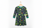 Child wearing a dinosaur-patterned nightgown standing on a tiled floor.