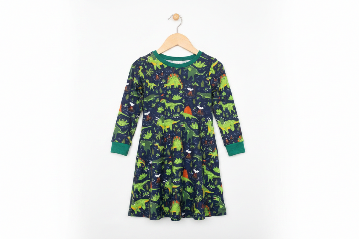 Child wearing a dinosaur-patterned nightgown standing on a tiled floor.