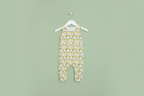 A baby romper with a yellow and white lemon pattern, hanging on a white plastic hanger against a plain white background. Snazzy Sproglets
