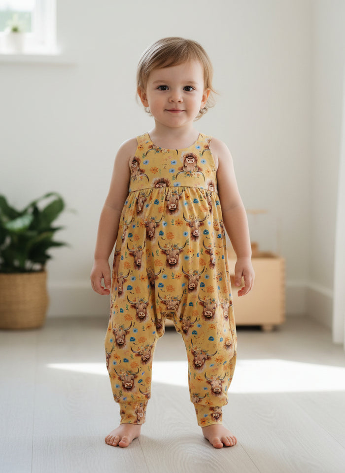 Child wearing a yellow romper with animal print 