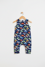A baby romper in navy blue with an all-over colorful airplane print, hanging from a wooden hanger against a plain light gray background. Snazzy Sproglets