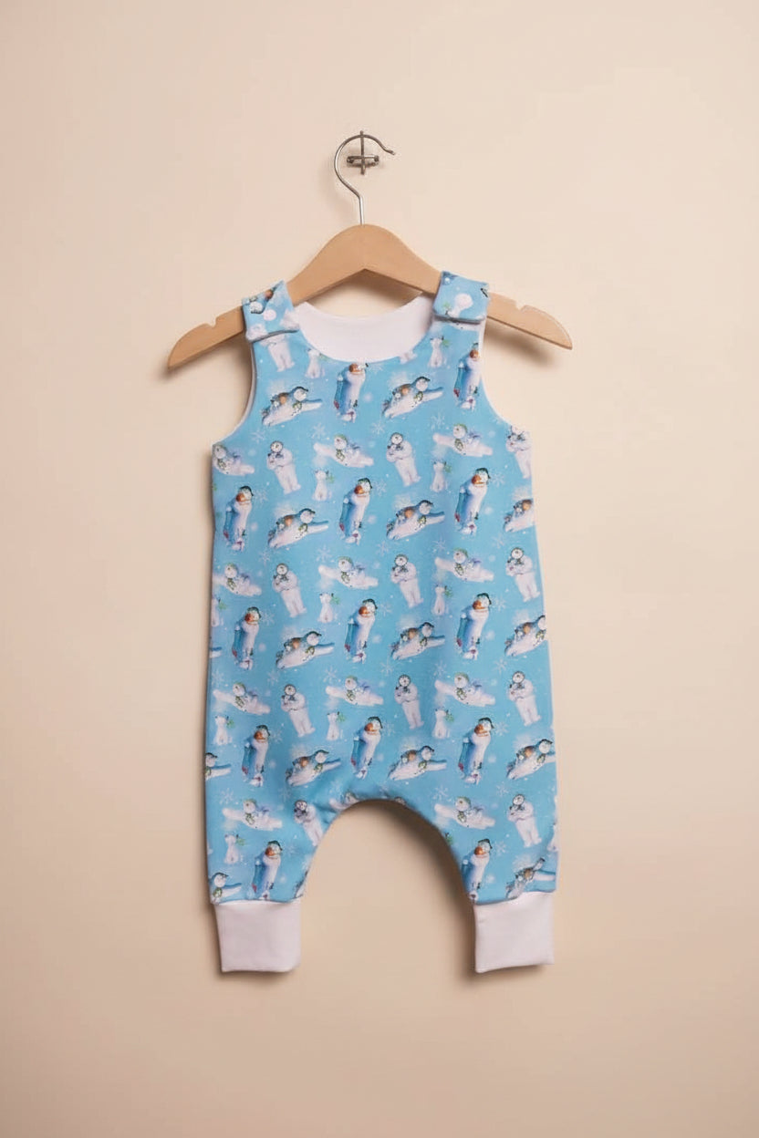 A light blue baby romper with a snowman print, hanging on a wooden hanger 