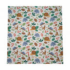 A close-up of a fabric with a colorful safari animal print featuring lions, elephants, monkeys, and tropical leaves on a light beige background.