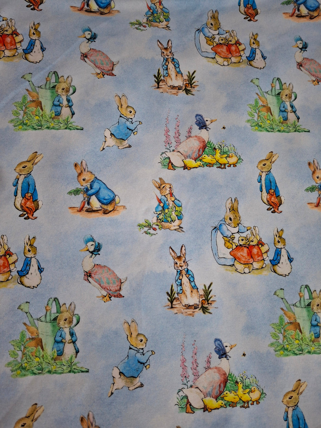 Fabric with illustrations of cartoon bunnies and ducks on a light blue background