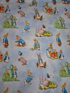 Fabric with illustrations of cartoon bunnies and ducks on a light blue background