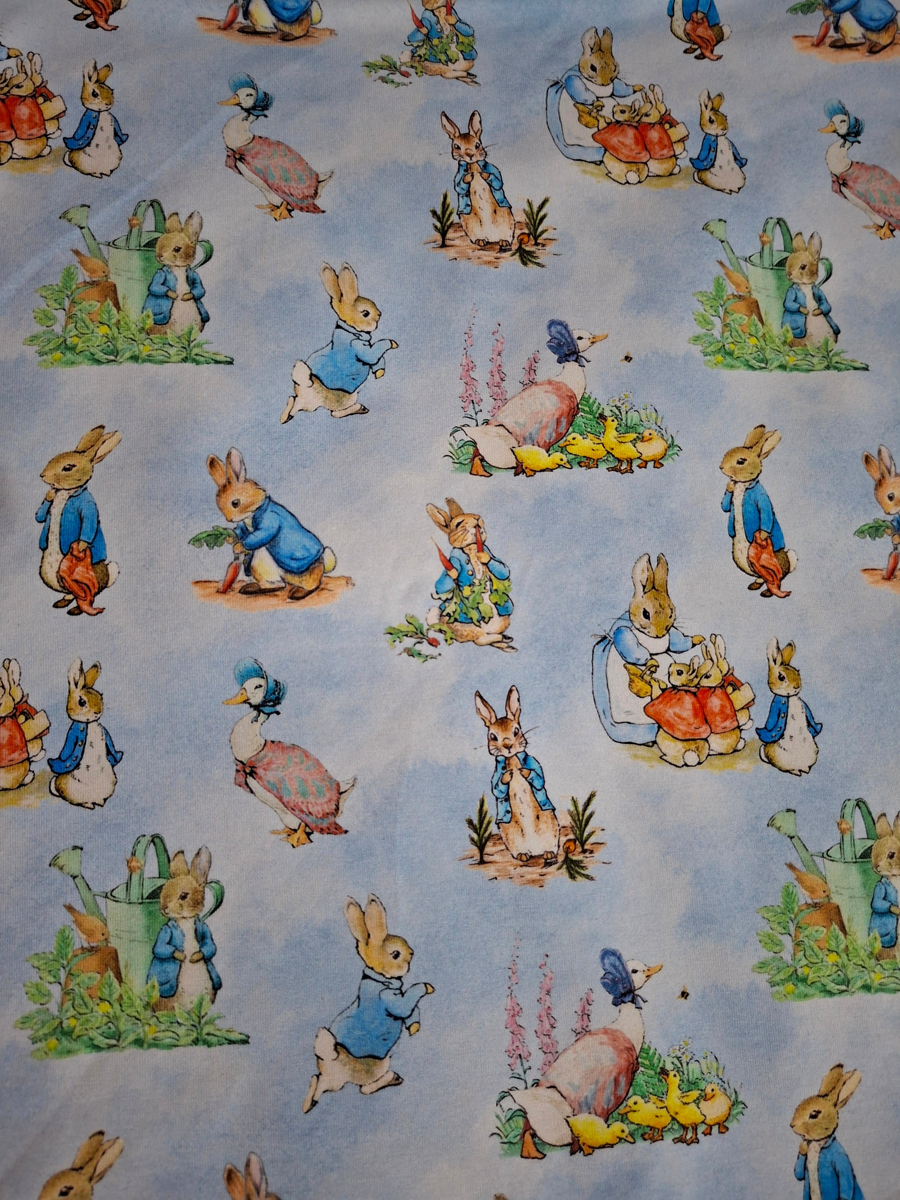 Fabric with illustrations of cartoon bunnies and ducks on a light blue background