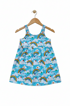 A sleeveless baby dress with a light blue background, featuring a repeating pattern of white clouds, colorful rainbows, and small hearts.