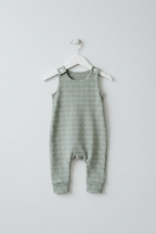 A sage green baby romper with a white windowpane grid pattern, hanging on a white plastic hanger against a light gray background. Snazzy Sproglets