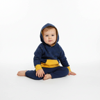 Baby wearing a blue and yellow outfit with a hood on a white background
