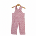 A baby romper in a pink and white gingham check pattern, hanging on a wooden hanger against a plain white background. Snazzy Sproglets