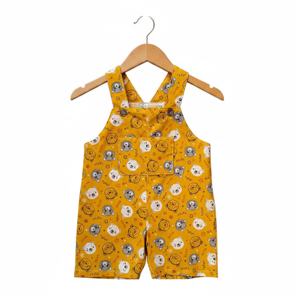A pair of yellow baby overalls with an all-over cartoon animal face print, featuring a front pocket and shoulder straps, shown against a plain white background.Snazzy Sproglets