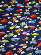 Fabric with colorful airplanes, helicopters, and clouds on a blue background