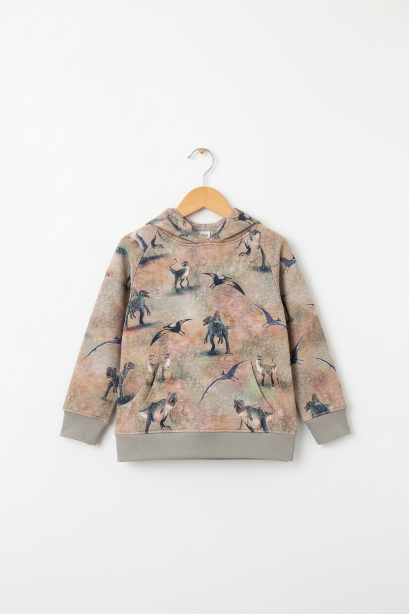 A children's hooded sweatshirt hanging on a wooden hanger against a plain white background. The sweatshirt has an all-over dinosaur print on a warm beige and light brown base, with solid gray ribbed cuffs and hem. Snazzy Sproglets