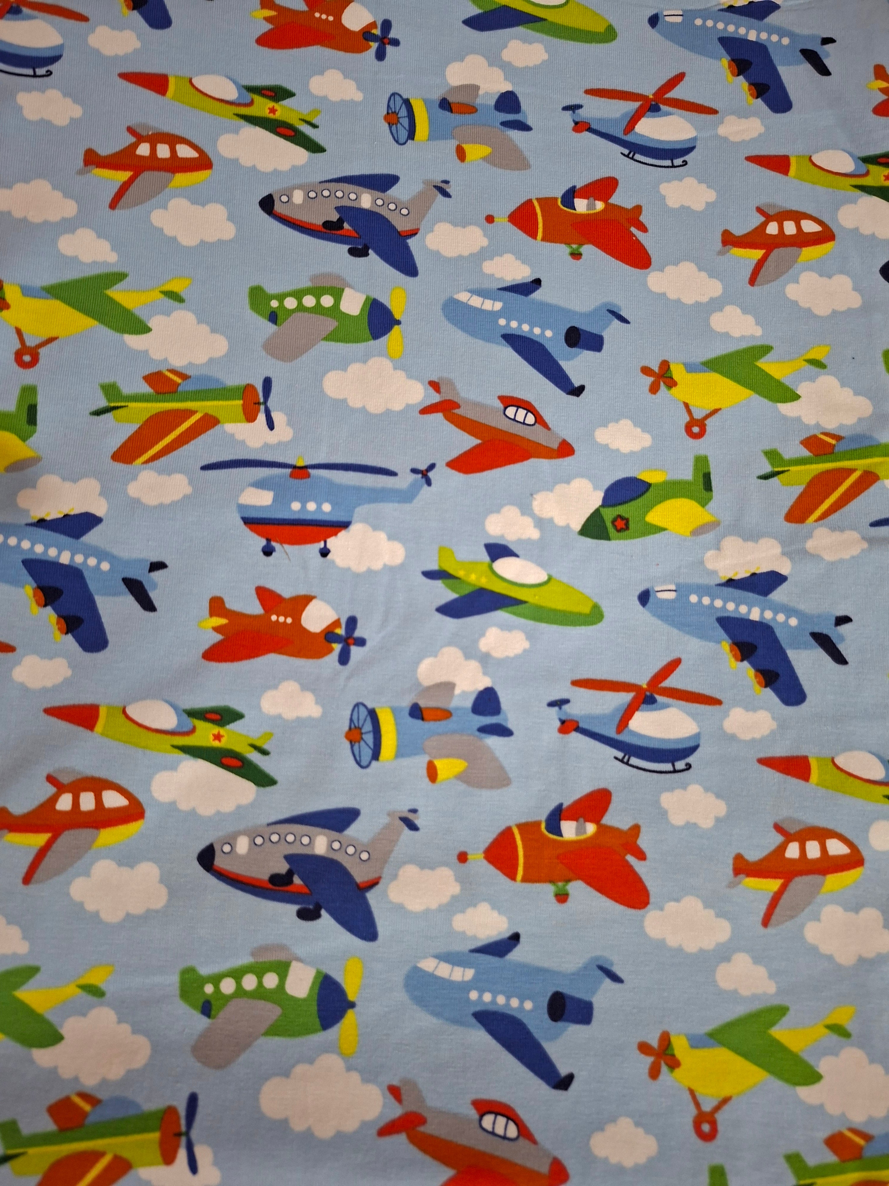 Fabric with colorful airplanes and helicopters on a blue background