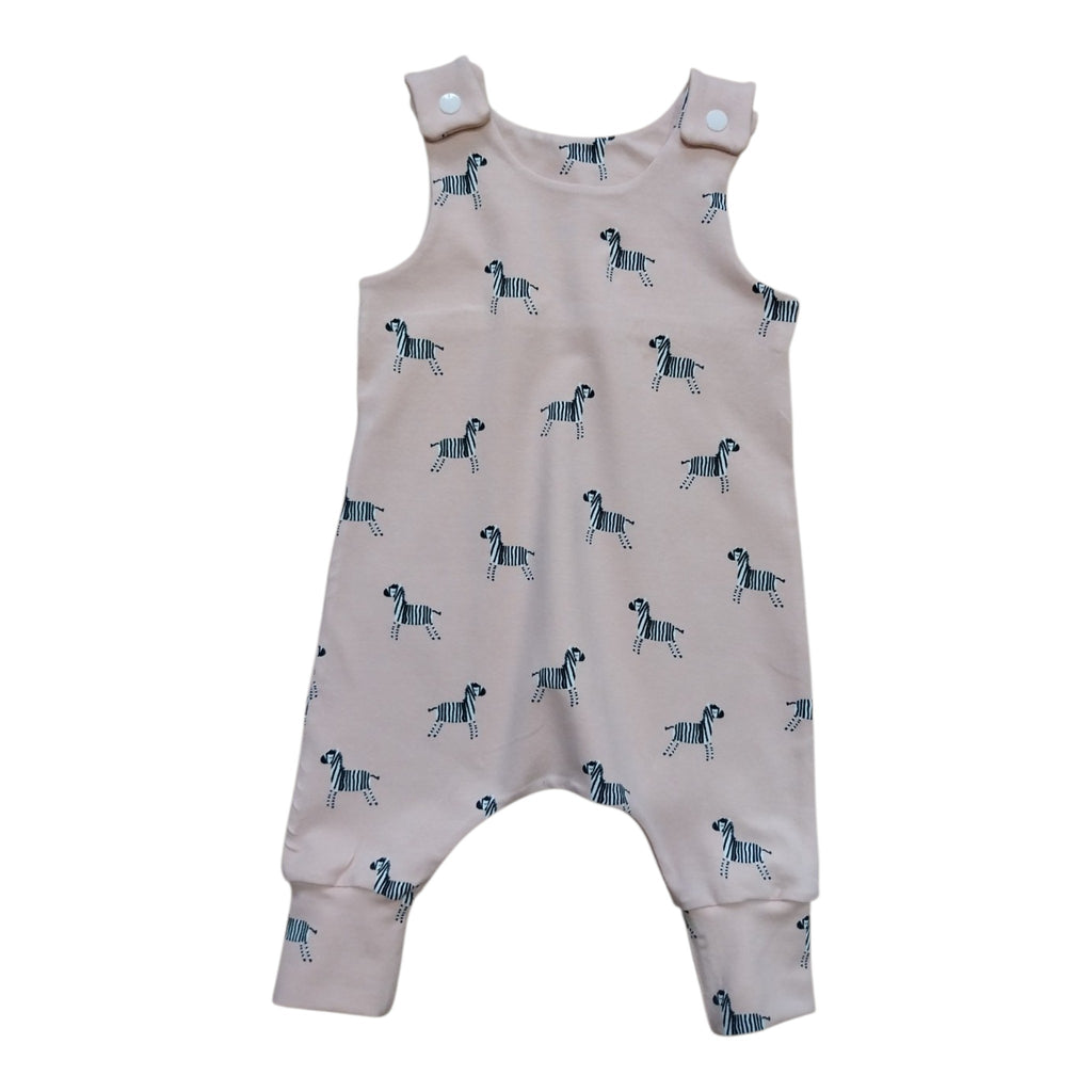 A baby romper in a light dusty pink color, featuring an all-over print of small black and white zebras. 