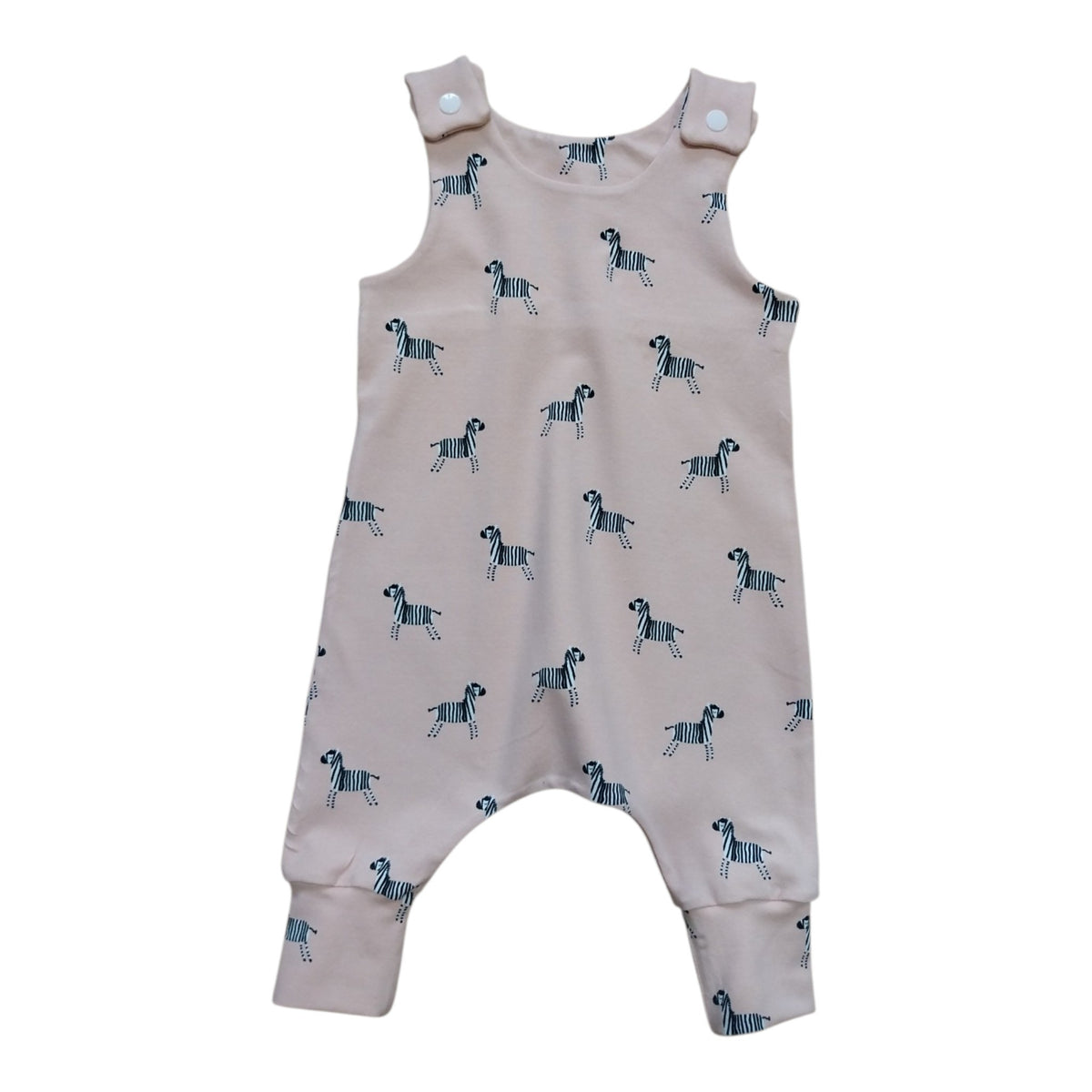 A baby romper in a light dusty pink color, featuring an all-over print of small black and white zebras. 