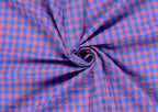A close-up of a blue and pink gingham fabric arranged in a spiral drape, showing the texture and pattern of the material. Snazzy Sproglets