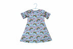 A short-sleeve baby t-shirt with a colorful repeating pattern of rainbows, clouds, and small hearts on a light pink background.