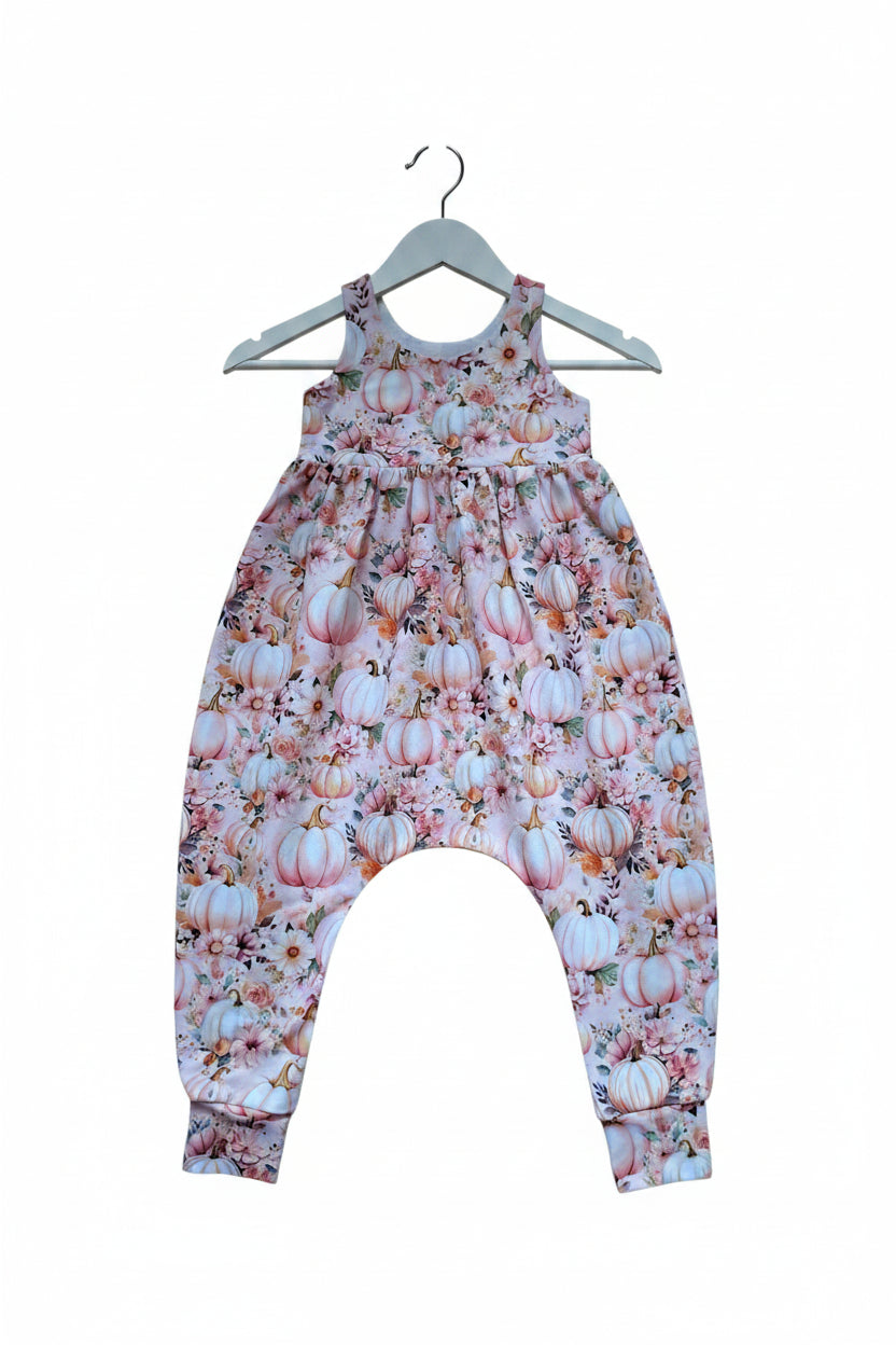 A baby romper with a light pink and white floral print featuring pumpkins, flowers, and leaves, shown flat against a white background.