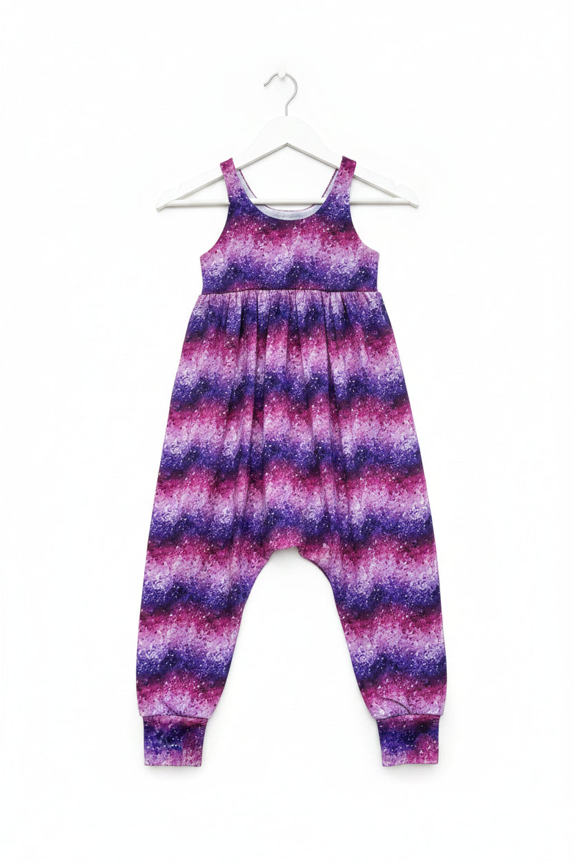 A sleeveless children's jumpsuit with a wavy, zigzag pattern in purple, magenta, and white, shown flat against a solid white background.
