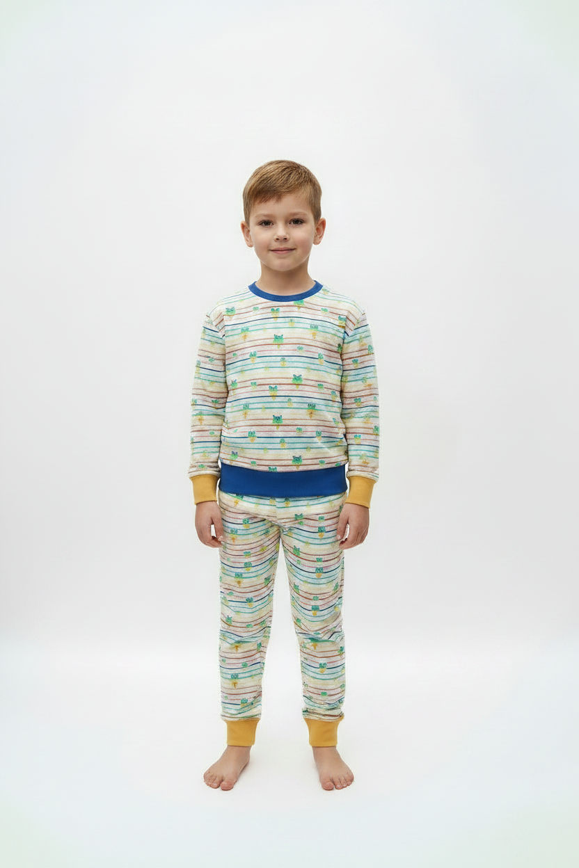 A young boy stands barefoot against a plain white studio background wearing a matching two-piece pajama set. The long-sleeve top and pants are cream-colored with thin multicolored horizontal stripes and small green butterfly motifs, finished with solid blue and mustard yellow trim at the collar, cuffs, and waistband.