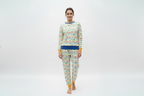 A woman modeling a matching two-piece pajama set with a colorful striped pattern and yellow cuffs, on a white studio background.