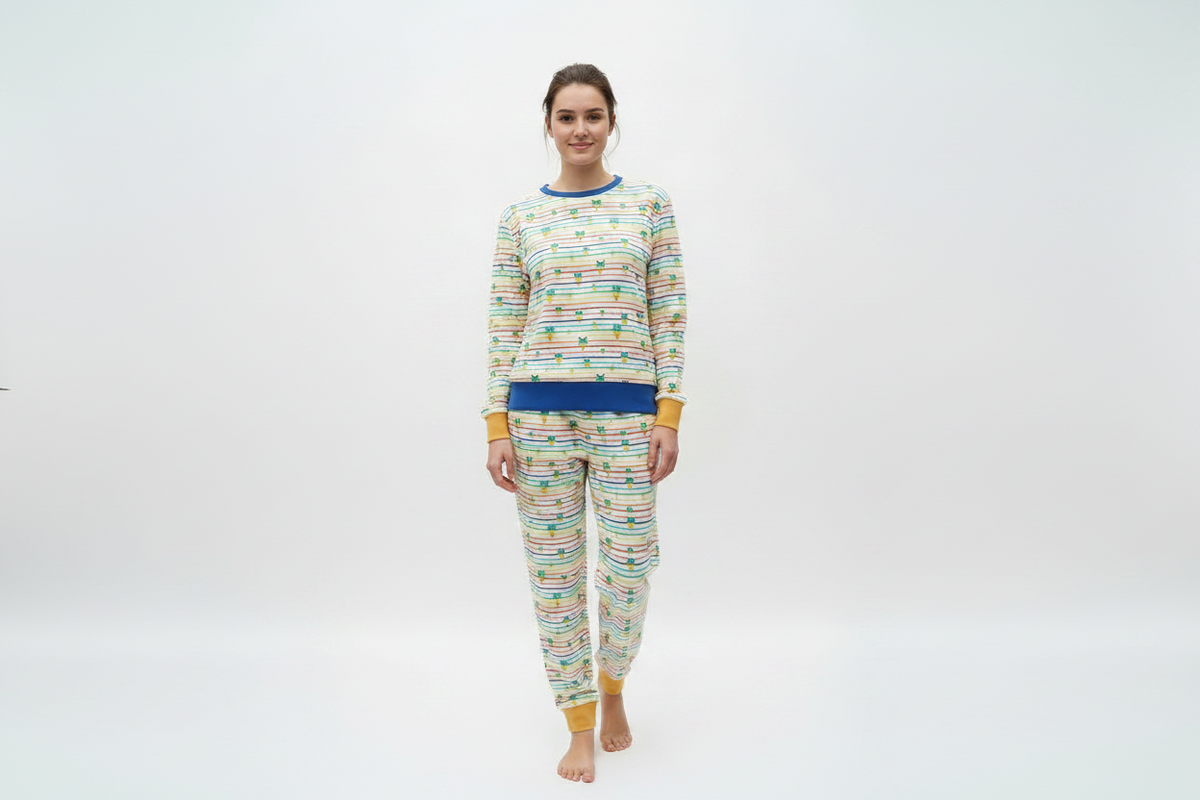 A woman modeling a matching two-piece pajama set with a colorful striped pattern and yellow cuffs, on a white studio background.