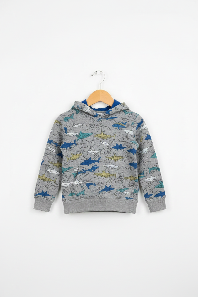 A children's gray hooded sweatshirt with an allover shark print in blue, yellow, and white, hanging on a wooden hanger against a plain white background.