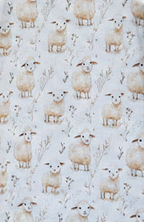 A close-up of fabric featuring a repeating pattern of cream-colored sheep on a light off-white background.snazzy sproglets