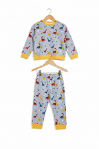 A children's two-piece pajama set consisting of a long-sleeve top and matching pants, hanging on wooden hangers against a plain white background. The pajamas feature a light gray base with a colorful dinosaur print in red, blue, yellow, and green, accented with yellow ribbed cuffs and hem. Snazzy Sproglets
