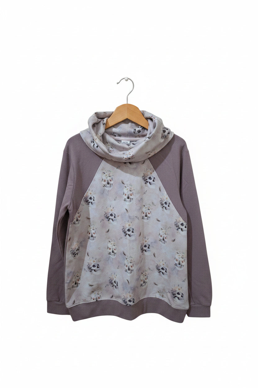 A women's long-sleeve top with a cowl neck, featuring solid taupe sleeves and hem, and a light gray floral and skull print overlay on the body and cowl.