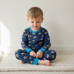 Child wearing blue pajamas with animal pattern sitting on a white surface