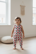 sleeveless one-piece jumpsuit with a strawberry and green leaf print on a pale pink background. snazzy sproglets