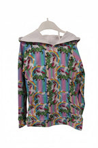 A long-sleeve hoodie with a colorful repeating pattern of green dinosaurs and rainbows, featuring a contrasting light gray hood lining, shown on a white hanger against a white background.