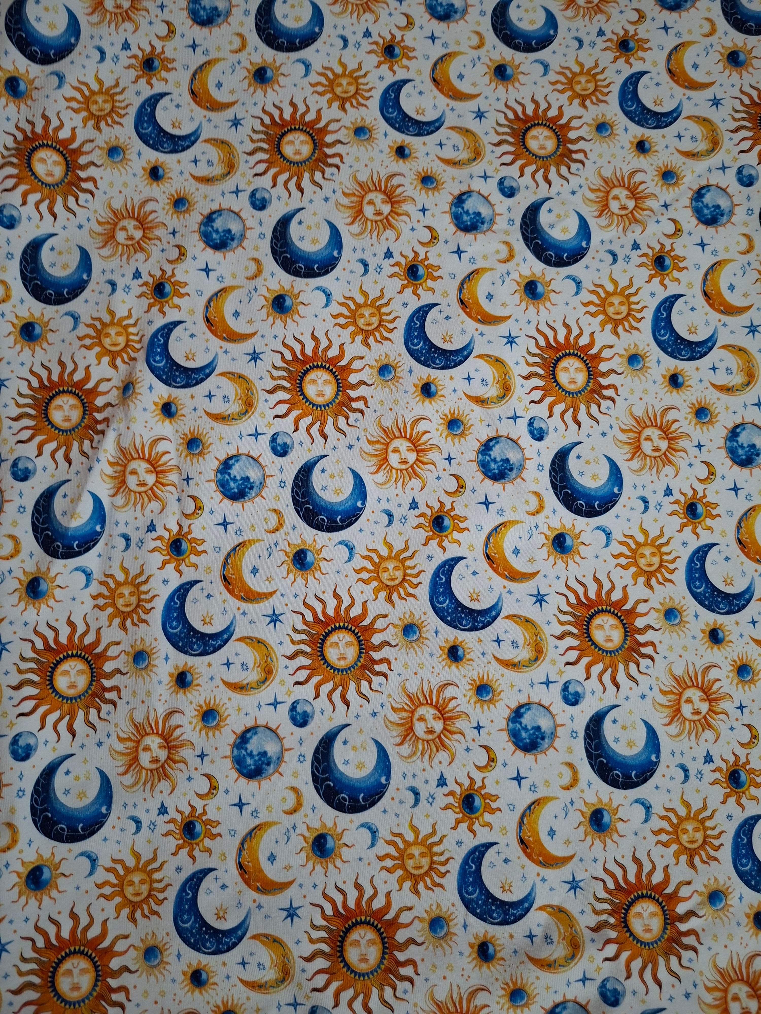 Pattern of suns, moons, and stars on a fabric background