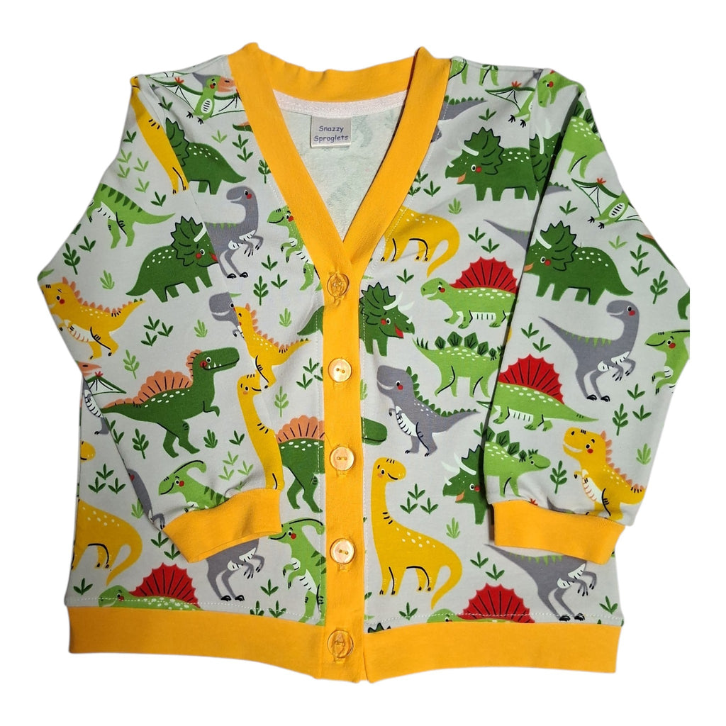 A children's long-sleeve cardigan with a colorful dinosaur print on a light green background, featuring a bright yellow trim and buttons.